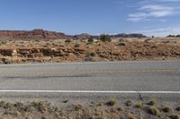 a long road stretches through a desert area with mountains in the background and a desert landscape in the foreground