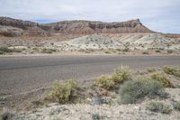 an empty dirt road is shown in front of a desert area with mountains and rocks