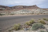 an empty dirt road is shown in front of a desert area with mountains and rocks