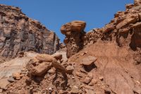 the top of a rocky hill covered in lots of brown rocks and sparse grass near a blue sky