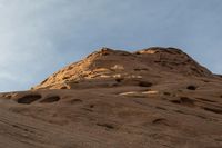 the sky is partly cloudy and blue above the mountain with small holes, like an eye