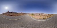 a wide shot is shown of an empty road in the desert with a mountain in the background