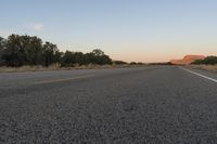 a long empty road with mountains in the distance with a car in the foreground