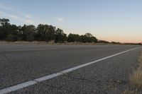 a long empty road with mountains in the distance with a car in the foreground