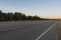 a long empty road with mountains in the distance with a car in the foreground