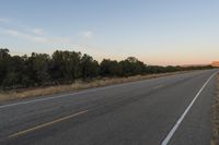 a long empty road with mountains in the distance with a car in the foreground