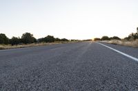 a long empty road with mountains in the distance with a car in the foreground