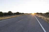 a long empty road with mountains in the distance with a car in the foreground