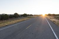 a long empty road with mountains in the distance with a car in the foreground