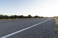 a long empty road with mountains in the distance with a car in the foreground