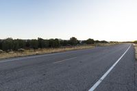 a long empty road with mountains in the distance with a car in the foreground