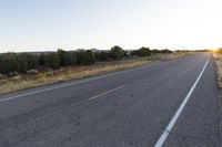 a long empty road with mountains in the distance with a car in the foreground