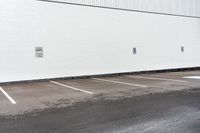 a red stop sign sitting next to a white building with parking spaces on the side