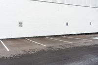 a red stop sign sitting next to a white building with parking spaces on the side