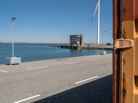 red and white lighthouse and street sign on side of road with wind turbines in background