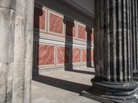 the stone wall is red and white with three columns and a column that has turned to be marble