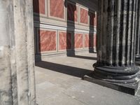 the stone wall is red and white with three columns and a column that has turned to be marble