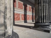 the stone wall is red and white with three columns and a column that has turned to be marble