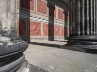 the stone wall is red and white with three columns and a column that has turned to be marble