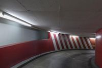 red and white wall by the road inside a tunnel with light on it's top