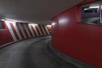 red and white wall by the road inside a tunnel with light on it's top