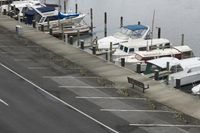 several boats are docked in the marina on a lake side road near the water and benches