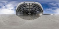 a reflection of a factory in a fisheye lens by an airplane hangar with a ramp underneath