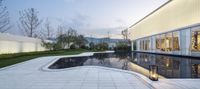 an outdoor area with a reflection in the pool and some windows on the side of it