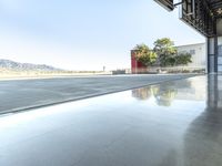 the reflection on the pavement shows a jet plane on the ground below it with mountains in the background