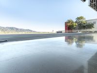 the reflection on the pavement shows a jet plane on the ground below it with mountains in the background