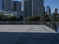 the reflection of buildings in water is shown on the ground next to an open area with water and benches