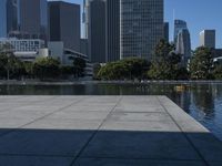 the reflection of buildings in water is shown on the ground next to an open area with water and benches