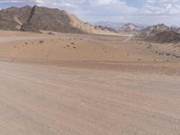 a dirt road runs through the desert land in a remote area with mountains around it