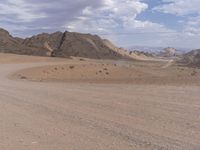 a dirt road runs through the desert land in a remote area with mountains around it