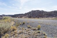 the road is going to an empty rocky area and has many rocks all around it