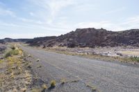 the road is going to an empty rocky area and has many rocks all around it