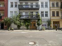 an apartment building with a balcony above a street on the side of the road in front of it