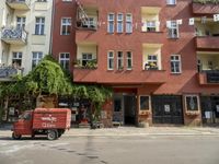 an apartment building with a balcony above a street on the side of the road in front of it