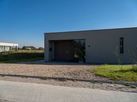 a small building sits near the road and grassy area in front of it, with an overhang overhang