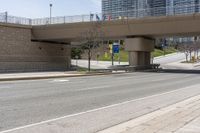 an empty highway with buildings and an overpass above it at the base of a bridge