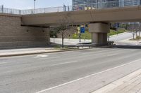 an empty highway with buildings and an overpass above it at the base of a bridge