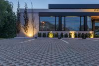 the front of a restaurant with lights and trees in the parking lot in front of it