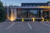 the front of a restaurant with lights and trees in the parking lot in front of it