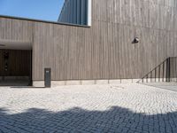 a concrete brick path in front of a building with a gray gate on one side