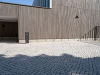 a concrete brick path in front of a building with a gray gate on one side