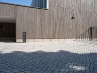 a concrete brick path in front of a building with a gray gate on one side