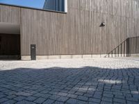 a concrete brick path in front of a building with a gray gate on one side