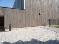 a concrete brick path in front of a building with a gray gate on one side