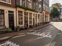 a street lined with buildings and benches on both sides of it on cobblestones