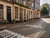 a street lined with buildings and benches on both sides of it on cobblestones